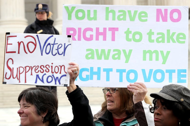 Protesters hold up signs reading, "End voter suppression now," and "You have no right to take away my right to vote."